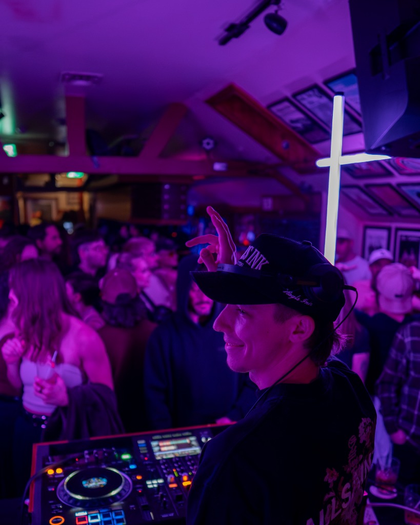Professional promotional portrait of a PEI DJ wearing cap under deep purple neon club lighting - Eastside Photography artist promo