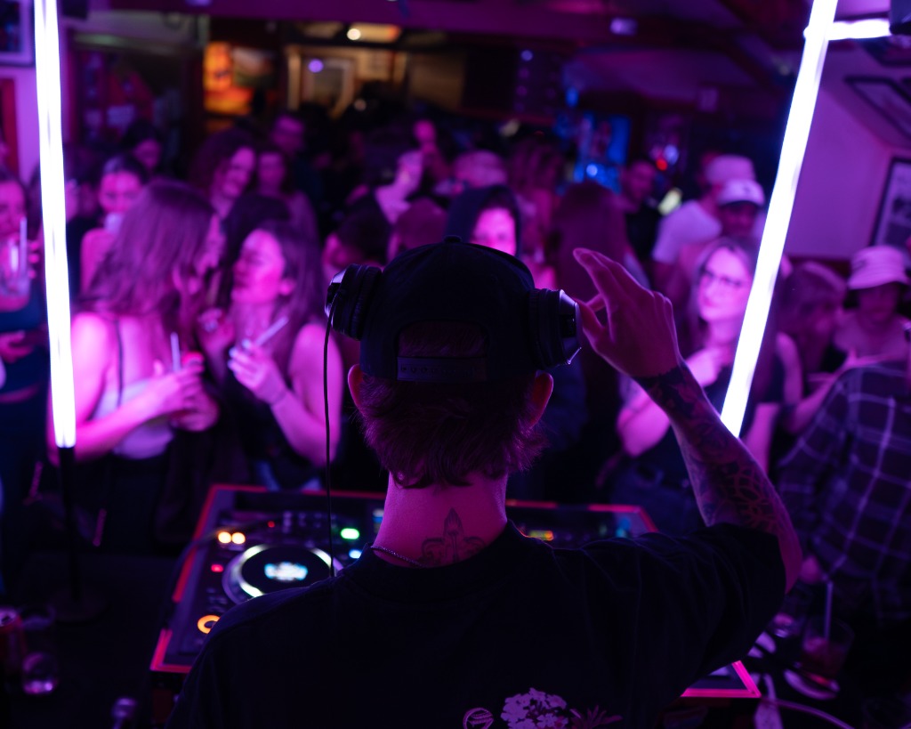 DJ perspective looking out at a dancing crowd at a PEI music festival with neon lights - Eastside Photography event coverage