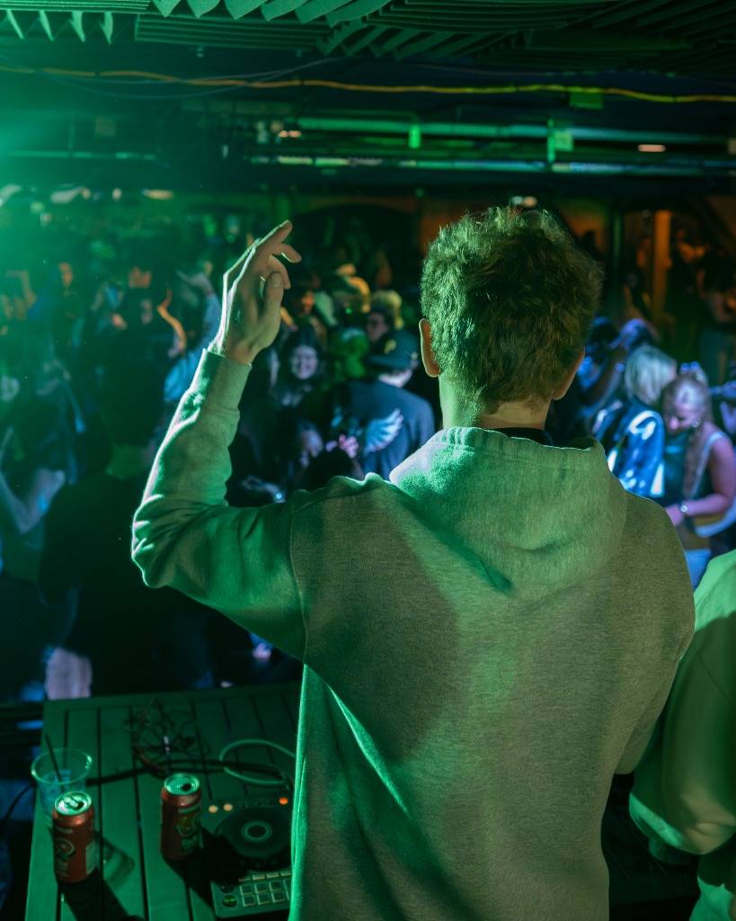 Professional DJ engaging with dance floor crowd under green neon club lighting in Prince Edward Island - Eastside Photography