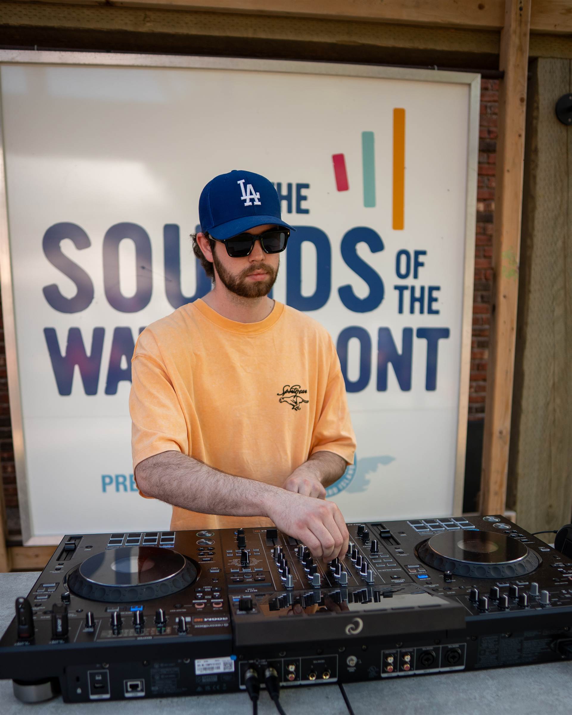 Smiling DJ in IAAB shirt lifting headphones Pioneer DJ waterfront golden hour PEI - Eastside Photography